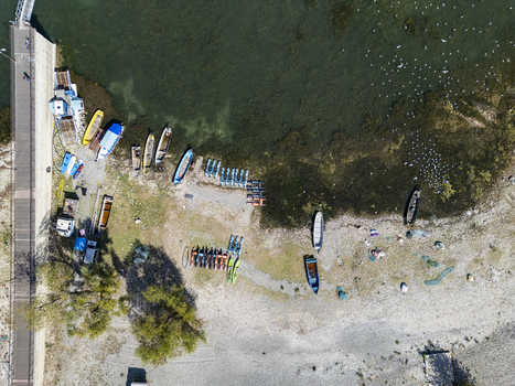Aerial view of the lakeshore at Moloja Shiroke with small boats kayaks and a pier along the rocky coast of Lake Shkodra in Shiroka Shkoder County Albania. Aerial view of the lakeshore at Moloja Shiroke with small boats kayaks and a pier along the rocky coast of Lake Shkodra in Shiroka Shkoder County Albania.