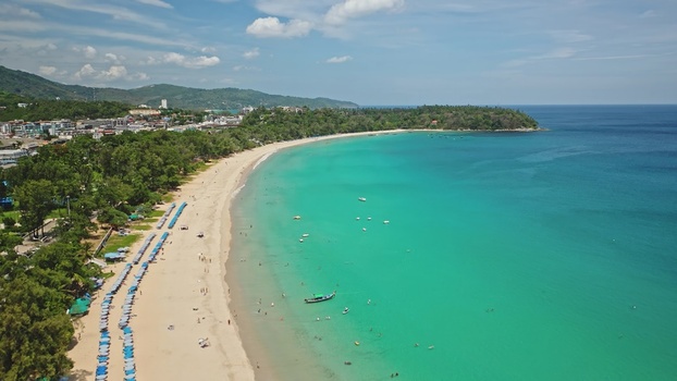 Aerial view of the turquoise waters and sandy coastline of Kata Beach with rows of umbrellas and lush trees Phuket Phuket Thailand. Aerial view of the turquoise waters and sandy coastline of Kata Beach with rows of umbrellas and lush trees Phuket Phuket Thailand.