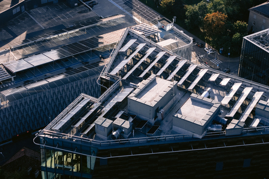 Aerial view of a modern building rooftop featuring rows of solar panels and HVAC units in Vilnius Vilnius County Lithuania.