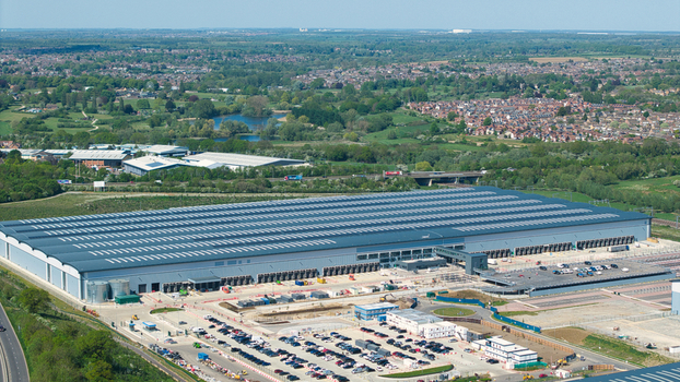 Aerial view of Symmetry Park distribution center with its massive warehouse large parking area and surrounding green landscape in Kettering England United Kingdom. Aerial view of Symmetry Park distribution center with its massive warehouse large parking area and surrounding green landscape in Kettering England United Kingdom.