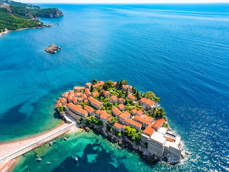 Aerial view of Sveti Stefan a historic islet with terracotta roofed buildings surrounded by turquoise Adriatic Sea waters Sveti Stefan Budva Municipality Montenegro.