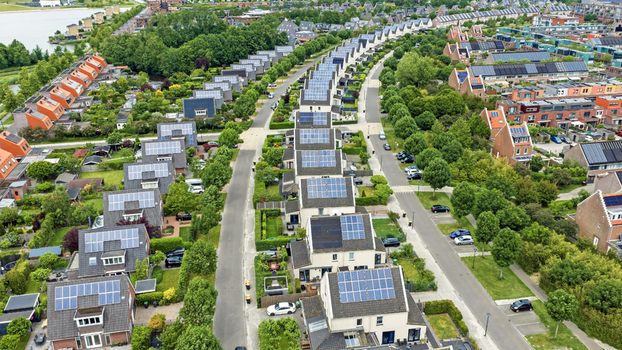 Aerial view of modern residential houses with solar panels on rooftops along curved streets and green trees in Heerhugowaard North Holland Netherlands. Aerial view of modern residential houses with solar panels on rooftops along curved streets and green trees in Heerhugowaard North Holland Netherlands.
