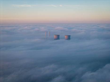 Aerial view of RWE Clauscentrale power plant with cooling towers and chimneys emerging from a thick sea of clouds under a soft morning sky in Maasbracht Limburg Netherlands. Aerial view of RWE Clauscentrale power plant with cooling towers and chimneys emerging from a thick sea of clouds under a soft morning sky in Maasbracht Limburg Netherlands.