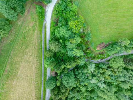 Aerial view of a winding road cutting through the lush green forests and meadows of Nationalpark Gesause in Admont Steiermark Austria.