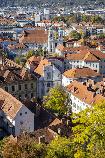 View of terracotta roofs cascading down towards baroque churches amidst the autumn foliage a timeless tableau of urban harmony Graz Styria Austria. View of terracotta roofs cascading down towards baroque churches amidst the autumn foliage a timeless tableau of urban harmony Graz Styria Austria.