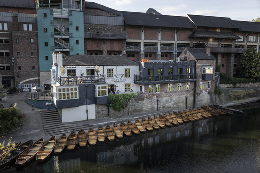 Durham United Kingdom 13 July 2026 View of the Durham Boat Club building situated along the riverbank with numerous rowing boats moored in a line. Durham United Kingdom 13 July 2026 View of the Durham Boat Club building situated along the riverbank with numerous rowing boats moored in a line.