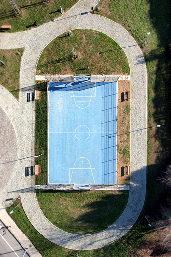 Aerial view of a blue basketball court surrounded by a gravel walking path and green lawn in Turin Piedmont Italy. Aerial view of a blue basketball court surrounded by a gravel walking path and green lawn in Turin Piedmont Italy.