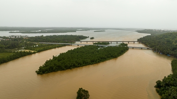 Aerial view of the Sharavathi River flowing around a lush green island with bridges spanning the water in Honnavar Karnataka India.