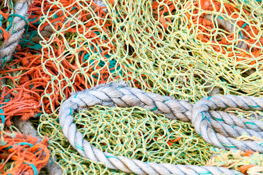View of colorful orange yellow and green fishing nets tangled with a thick braided rope in Canada. View of colorful orange yellow and green fishing nets tangled with a thick braided rope in Canada.