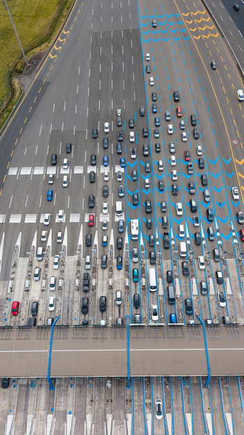 Aerial view of Milano Sud toll plaza on the A1 motorway with vehicle traffic highway infrastructure and blue lane markings in Melegnano Lombardy Italy.