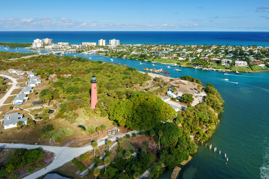 Aerial view of the Jupiter Inlet Lighthouse stands tall against the vivid blue of the Atlantic surrounded by lush greenery and sparkling waters Jupiter Florida United States.