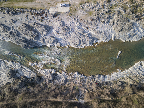 Aerial view of Lume i Kirit flowing through rocky terrain with clear water and a white car parked on the bank in Shkoder Qarku i Shkoderes Albania. Aerial view of Lume i Kirit flowing through rocky terrain with clear water and a white car parked on the bank in Shkoder Qarku i Shkoderes Albania.