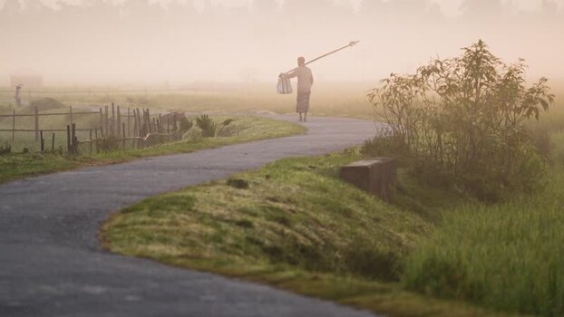 View of a man walking on a foggy rural road in Bogura Bangladesh.