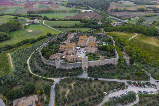Aerial view of the historic walled town of Monteriggioni surrounded by olive groves vineyards and rolling hills in Monteriggioni Tuscany Italy.