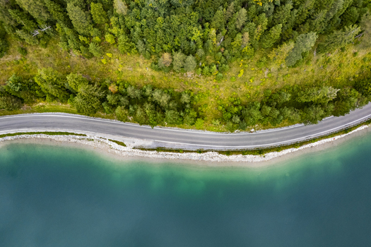 Aerial view of the winding road tracing the turquoise lake s edge embraced by verdant forests a symphony of colors Plansee Tyrol Austria. Aerial view of the winding road tracing the turquoise lake s edge embraced by verdant forests a symphony of colors Plansee Tyrol Austria.