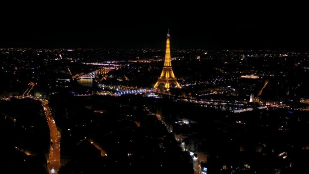 Aerial view of the illuminated Eiffel Tower at night surrounded by glowing city lights and the Seine river winding through the urban landscape in Paris Ile de France France. Aerial view of the illuminated Eiffel Tower at night surrounded by glowing city lights and the Seine river winding through the urban landscape in Paris Ile de France France.