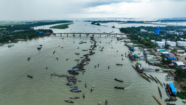 Baghabari Bangladesh 20 August 2022 Aerial view of Baghabari river port with numerous traditional wooden boats and cargo vessels navigating the waterway under a cloudy sky.