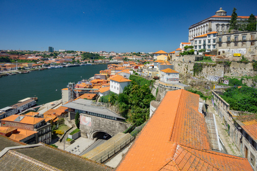 Aerial view of the Douro River snaking through Porto reflecting the clear sky with terracotta roofs and historic buildings cascading down to the waterfront Porto Porto District Portugal. Aerial view of the Douro River snaking through Porto reflecting the clear sky with terracotta roofs and historic buildings cascading down to the waterfront Porto Porto District Portugal.