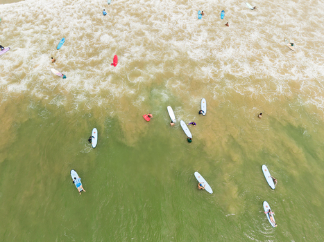 Aerial view of surfers on colorful boards waiting for waves in the turquoise ocean water with white foam in Weligama Southern Province Sri Lanka.
