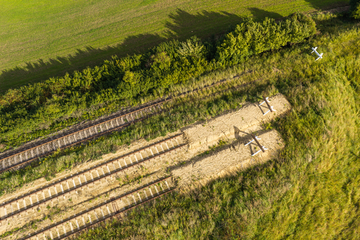 Aerial view of railway tracks cutting through a grassy rural landscape with trees and sandy embankments Pelplin Pomeranian Voivodeship Poland.