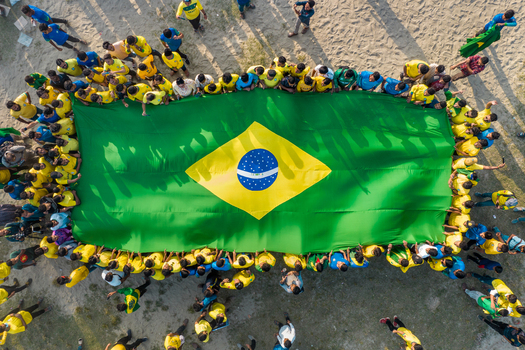 Bogura Bangladesh 18 November 2022 Aerial view of a large group of people holding a massive Brazilian flag on a sandy ground.