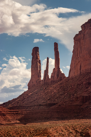 Oljato Monument Valley Arizona United States 05 September 2018 View of the Three Sisters rock formation featuring towering red sandstone spires against a blue sky with clouds. Oljato Monument Valley Arizona United States 05 September 2018 View of the Three Sisters rock formation featuring towering red sandstone spires against a blue sky with clouds.