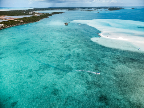 Aerial view of the Man O War Cay Sandbar with turquoise waters and white sand near the lush coastline in Rolletown Exuma The Bahamas. Aerial view of the Man O War Cay Sandbar with turquoise waters and white sand near the lush coastline in Rolletown Exuma The Bahamas.