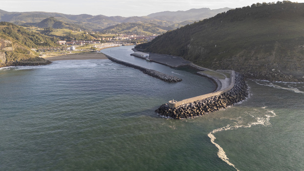 Aerial view of Antilla beach with its stone breakwater extending into the sea surrounded by green hills and coastal landscape in Gipuzkoa Basque Country Spain.