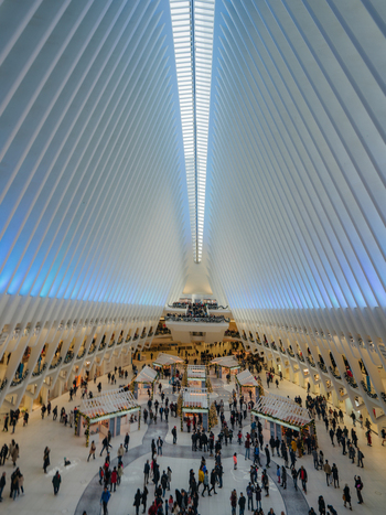 View of the Oculus interior with its distinctive white ribbed structure and high vaulted ceiling featuring people walking through the spacious transit hub in New York New York United States.