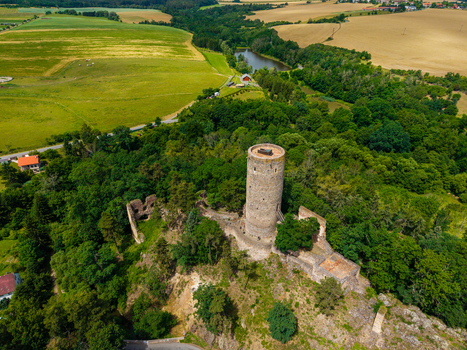 Aerial view of the historic Tocnik Castle ruins featuring its prominent stone tower surrounded by lush green forests and rolling agricultural fields in Tocnik Stredocesky kraj Czechia. Aerial view of the historic Tocnik Castle ruins featuring its prominent stone tower surrounded by lush green forests and rolling agricultural fields in Tocnik Stredocesky kraj Czechia.