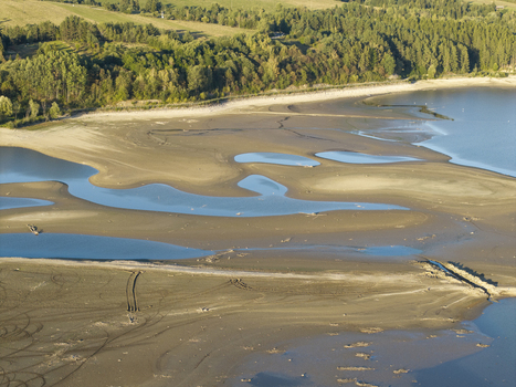 Aerial view of Lake Czorsztynskie with exposed sandy banks and low water levels surrounded by lush green forests in Nowy Targ County Lesser Poland Voivode Poland. Aerial view of Lake Czorsztynskie with exposed sandy banks and low water levels surrounded by lush green forests in Nowy Targ County Lesser Poland Voivode Poland.