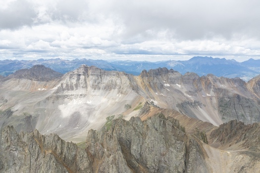 Aerial view of Mount Sneffels in the San Juan Mountains featuring rugged rocky peaks steep slopes and a cloudy sky over the alpine landscape in Ouray County Colorado United States. Aerial view of Mount Sneffels in the San Juan Mountains featuring rugged rocky peaks steep slopes and a cloudy sky over the alpine landscape in Ouray County Colorado United States.