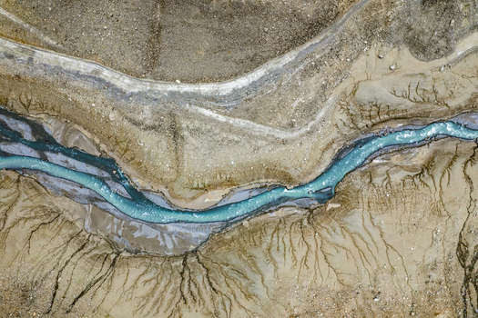 Aerial view of a turquoise glacial river flowing through sediment rich banks with intricate erosion patterns in the alpine landscape of Prutz Tyrol Austria. Aerial view of a turquoise glacial river flowing through sediment rich banks with intricate erosion patterns in the alpine landscape of Prutz Tyrol Austria.