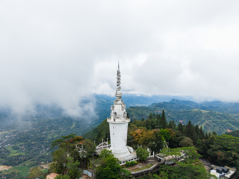 Aerial view of the unique spiral Ambuluwawa Tower surrounded by lush green hills and misty clouds in Gampola Central Province Sri Lanka. Aerial view of the unique spiral Ambuluwawa Tower surrounded by lush green hills and misty clouds in Gampola Central Province Sri Lanka.