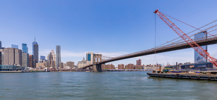 View of the Brooklyn Bridge with a construction crane on a barge in the East River against the Manhattan skyline in New York New York United States. View of the Brooklyn Bridge with a construction crane on a barge in the East River against the Manhattan skyline in New York New York United States.