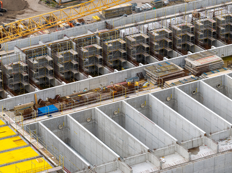 Aerial view of the Klarwerk Ruhleben construction site featuring large concrete basins scaffolding and yellow formwork in Berlin Berlin Germany.