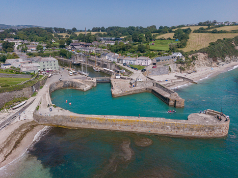 Aerial view of the historic stone harbour in Charlestown with small boats turquoise water and surrounding coastal village buildings in Charlestown Cornwall United Kingdom. Aerial view of the historic stone harbour in Charlestown with small boats turquoise water and surrounding coastal village buildings in Charlestown Cornwall United Kingdom.