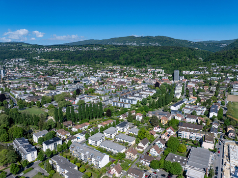 Aerial view of the residential district of Boezingenfeld Champ with modern apartment buildings and lush green trees against forested hills in Biel Bienne Canton of Bern Switzerland.