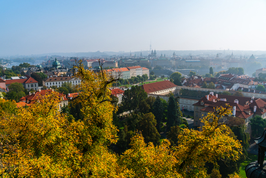 View of the historic cityscape of Prague with red tiled rooftops autumn foliage and lush green trees in Prague Prague Czechia.