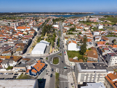 Aerial view of a bustling town center with white tent busy roundabout and terracotta roofs against distant waters Ilhavo Aveiro Portugal. Aerial view of a bustling town center with white tent busy roundabout and terracotta roofs against distant waters Ilhavo Aveiro Portugal.