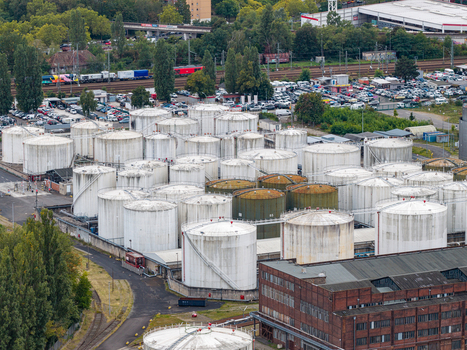 Aerial view of TanQuid Tanklager Berlin featuring numerous large cylindrical industrial storage tanks railway tracks and surrounding greenery in Berlin Berlin Germany.