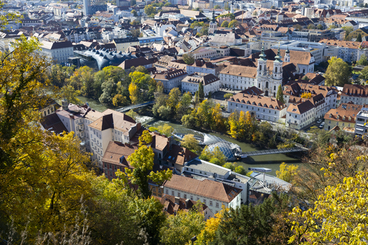 View of terracotta rooftops and creamy facades nestled along the Mur river with a blend of autumnal foliage and city life Graz Styria Austria. View of terracotta rooftops and creamy facades nestled along the Mur river with a blend of autumnal foliage and city life Graz Styria Austria.