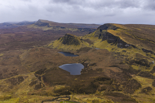 Aerial view of The Quiraing landslip with its dramatic rock formations and small lochs under a cloudy sky in the Isle of Skye Scotland United Kingdom. Aerial view of The Quiraing landslip with its dramatic rock formations and small lochs under a cloudy sky in the Isle of Skye Scotland United Kingdom.