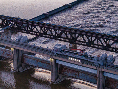 Aerial view of the industrial dam structure and rushing water of the Ohio River with a metal bridge and concrete pillars during dusk in Louisville Kentucky United States.