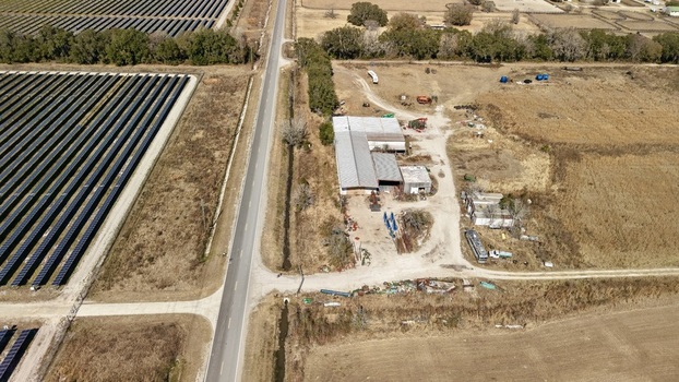 Aerial view of solar panels contrasting with the adjacent industrial complex and barren fields under a clear sky Elkton Florida United States. Aerial view of solar panels contrasting with the adjacent industrial complex and barren fields under a clear sky Elkton Florida United States.