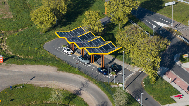 Bant Netherlands 23 April 2026 Aerial view of the Fastned Charging Station featuring its iconic yellow solar panel roof with electric cars parked in charging bays surrounded by lush green trees. Bant Netherlands 23 April 2026 Aerial view of the Fastned Charging Station featuring its iconic yellow solar panel roof with electric cars parked in charging bays surrounded by lush green trees.