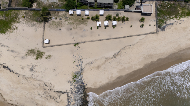 Aerial view of white cabanas on the sandy shore of Lekki Beach Road with ocean waves and palm trees in Lekki Lagos Nigeria. Aerial view of white cabanas on the sandy shore of Lekki Beach Road with ocean waves and palm trees in Lekki Lagos Nigeria.