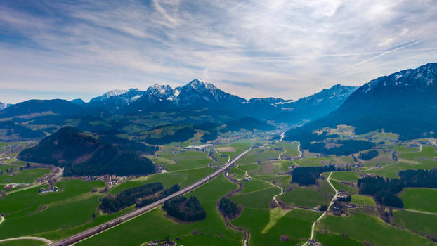 Aerial view of the vivid green Windischgarsten valley floor meeting rugged mountain peaks capped with snow under a vast expansive sky Windischgarsten Upper Austria Austria. Aerial view of the vivid green Windischgarsten valley floor meeting rugged mountain peaks capped with snow under a vast expansive sky Windischgarsten Upper Austria Austria.