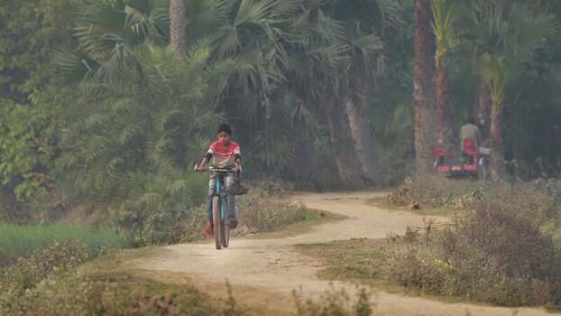 View of a boy riding a bicycle on a rural path in Bogura Bangladesh. View of a boy riding a bicycle on a rural path in Bogura Bangladesh.