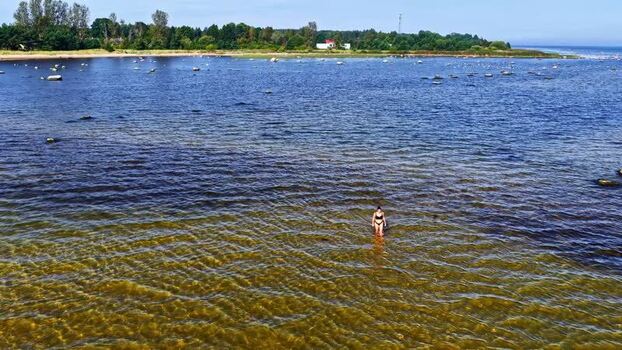 Aerial view of a woman wading in the shallow waters of Latvia. Aerial view of a woman wading in the shallow waters of Latvia.